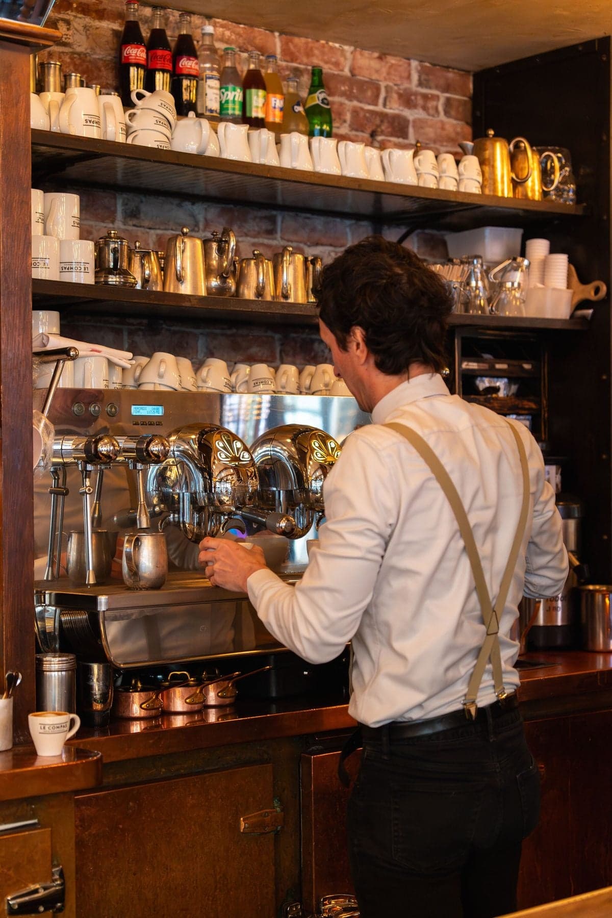 A waiter prepares coffee behind the counter
