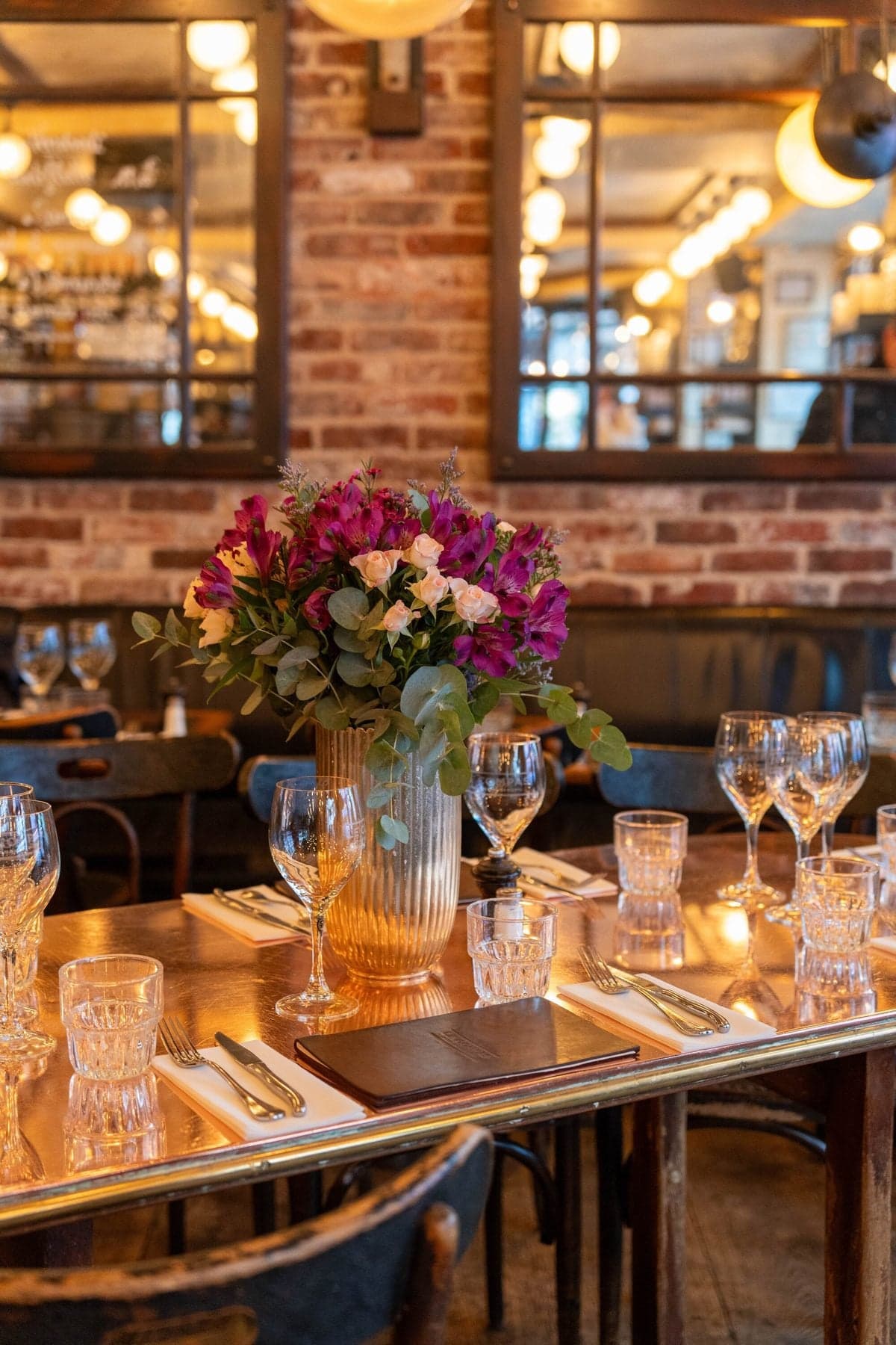 A laid table with a bouquet, glasses and warm light